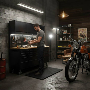 Man working at industrial tool workbench storage in garage workshop with motorcycle and tools