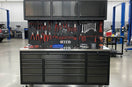 Large tool workbench with drawers and pegboard holding pliers and wrenches in a garage