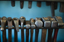 a row of metal tools sitting on top of a wooden rack