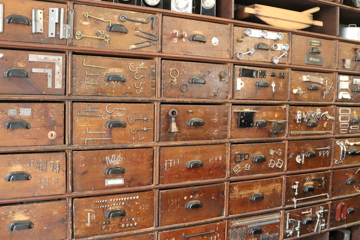 A wall of antique drawers filled with hardware.
