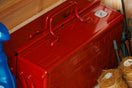 A red toolbox sits on a shelf with gardening supplies.