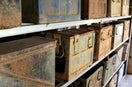 Rusty metal ammunition boxes on shelves in a storage room