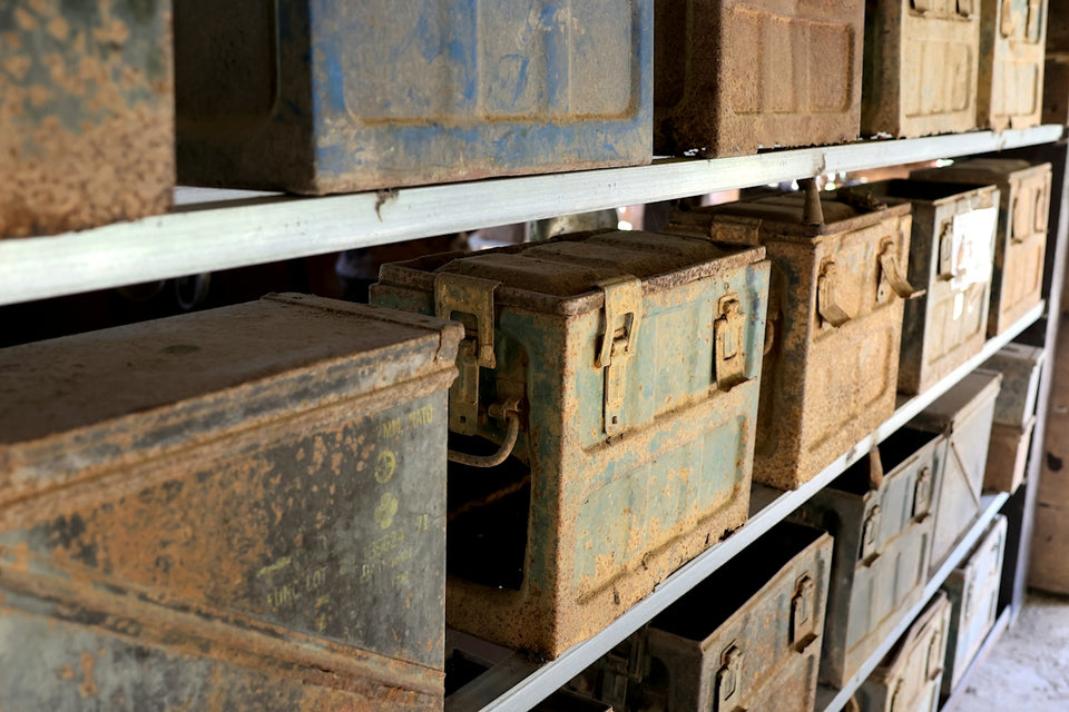 Rusty metal ammunition boxes on shelves in a storage room