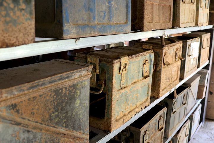 Rusty metal ammunition boxes on shelves in a storage room