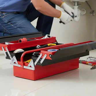 Open red plumber tool box with hand tools on bathroom floor, plumber working under sink