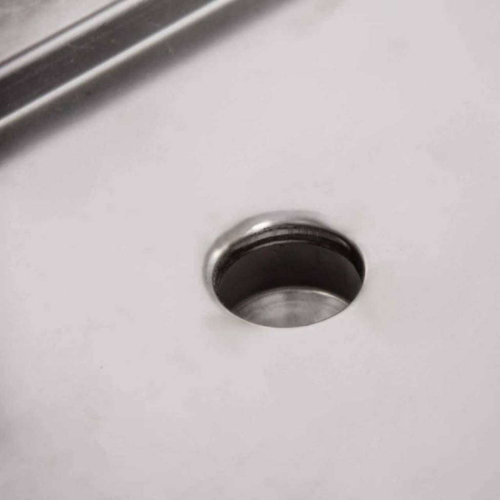 Close-up of a metal workbench surface with a round pre-drilled hole